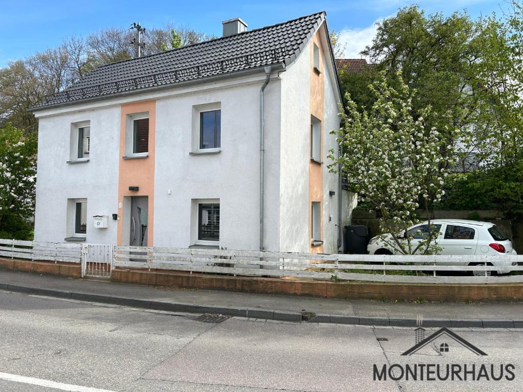 ein weißes Haus mit einem davor geparkt in der Unterkunft Monteurhaus in Unterkirchberg