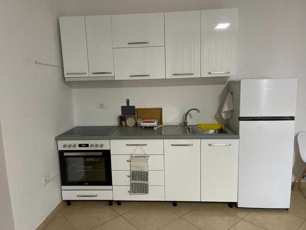 eine weiße Küche mit einer Spüle und einem Kühlschrank in der Unterkunft Sol Apartments in Tirana
