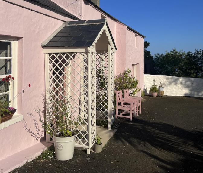 a white gazebo in the side of a house at The Pink Cottage (upstairs suite) & Secret Garden in Whitehead