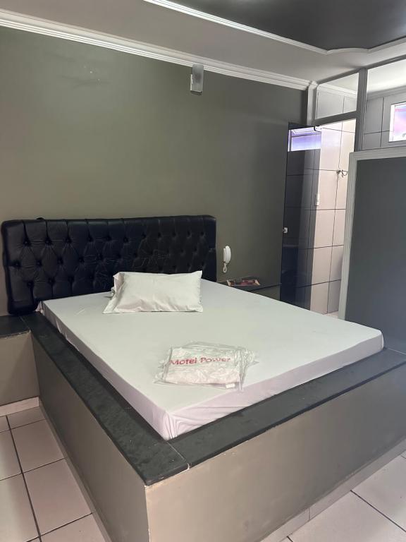 een slaapkamer met een groot bed met een zwart hoofdeinde bij Motel Power in Belo Horizonte