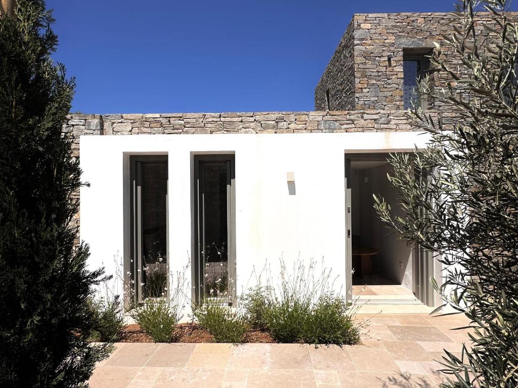 a white house with black windows and a stone wall at Egeo Paros in Kampos Paros