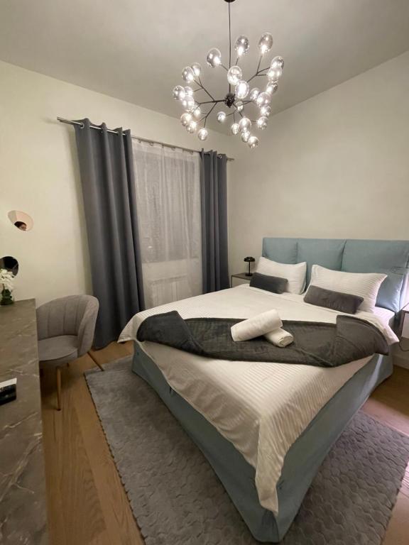 een slaapkamer met een groot bed en een kroonluchter bij Belgrade Waterfront Zvoncica Apartament in Belgrado