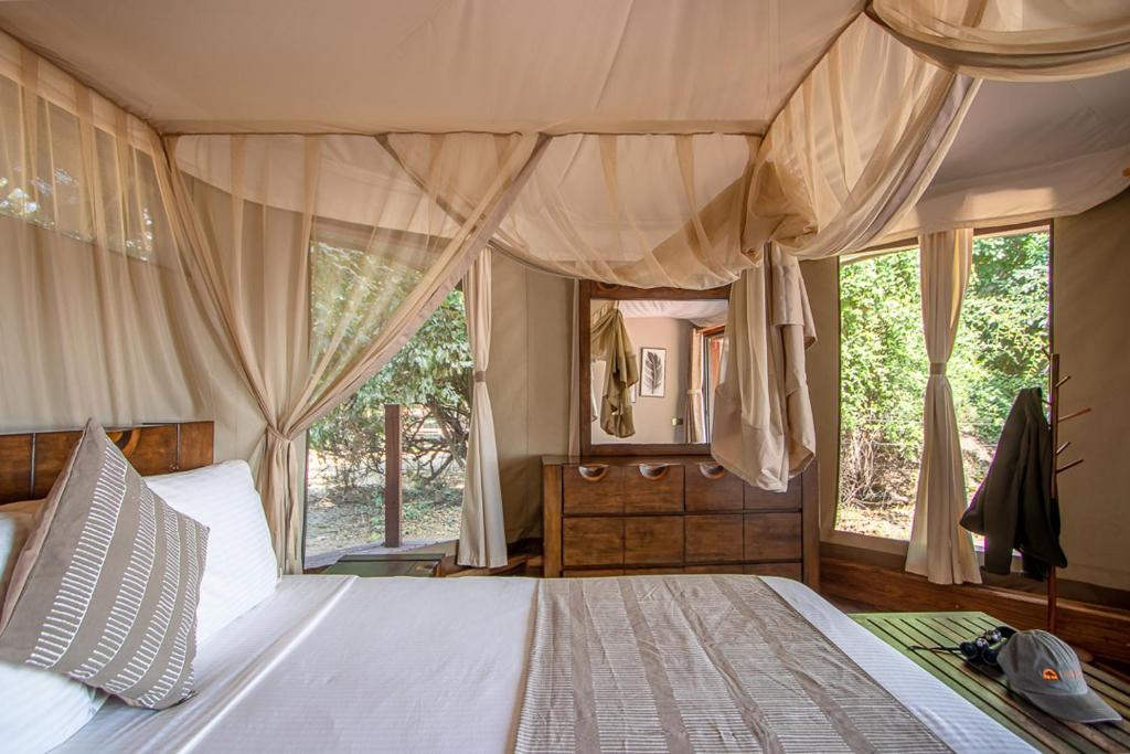 a bedroom with a large bed and a large window at Mopani Safari Lodge in Mfuwe