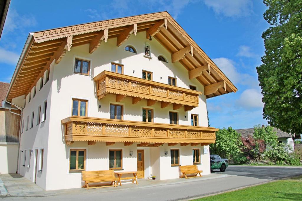 a large white building with wooden balconies and benches at Ferienhof Oberhuber in Staudach-Egerndach