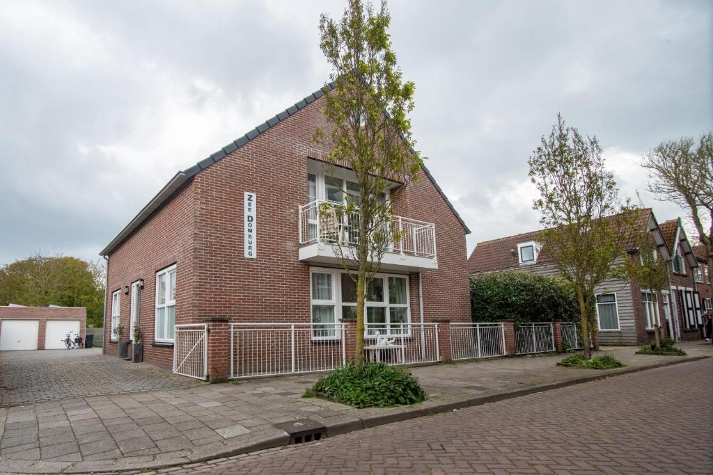 un edificio de ladrillo rojo con un árbol delante de él en Appartementen Zee Domburg, en Domburg