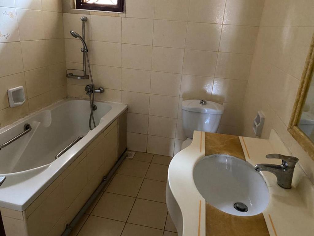 a bathroom with a tub and a toilet and a sink at Queens apartments in Entebbe