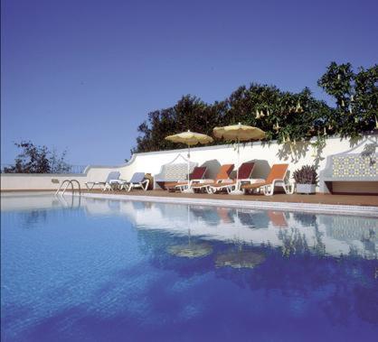 a group of chairs and umbrellas next to a swimming pool at Apartamentos Quinta Mae dos Homens in Funchal
