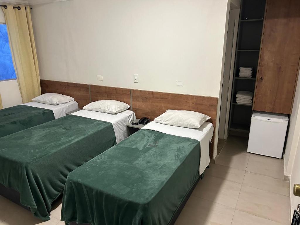 two beds in a hospital room with green sheets at Hotel Makuxis - Brigadeiro in São Paulo