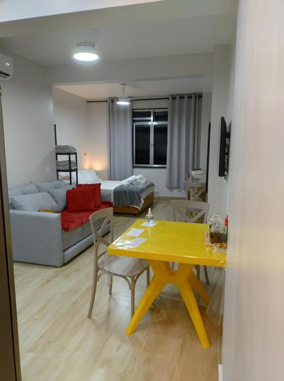 Hotel Studio novíssimo primeira quadra praia em Copacabana, a living room with a yellow table and a couch at Studio novíssimo primeira quadra praia em Copacabana in Rio de Janeiro