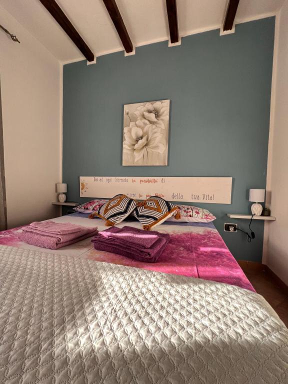 a bedroom with a large bed with pink sheets at Casa L ulivo in Santa Maria Navarrese