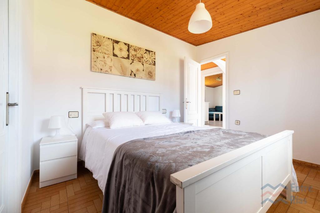 a white bedroom with a white bed and a wooden ceiling at A Casa de Carmen in Cangas de Morrazo