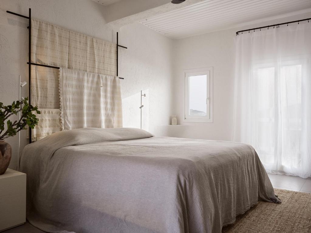 a white bedroom with a large bed and a window at Boheme Mykonos Town - Small Luxury Hotels of the World in Mikonos
