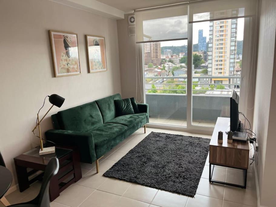 sala de estar con sofá verde y ventana grande en Departamento Nuevo con la comodidad que necesitas, en Temuco