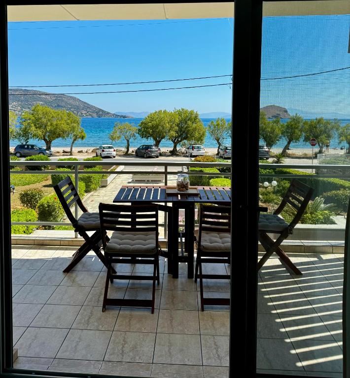 a table and chairs on a balcony with a view of the ocean at Seashore Happiness Apartments in Porto Rafti