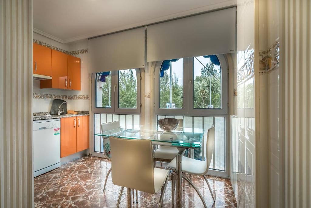 cocina con mesa de cristal y algunas ventanas en Apartamentos Las Brisas, en Santander