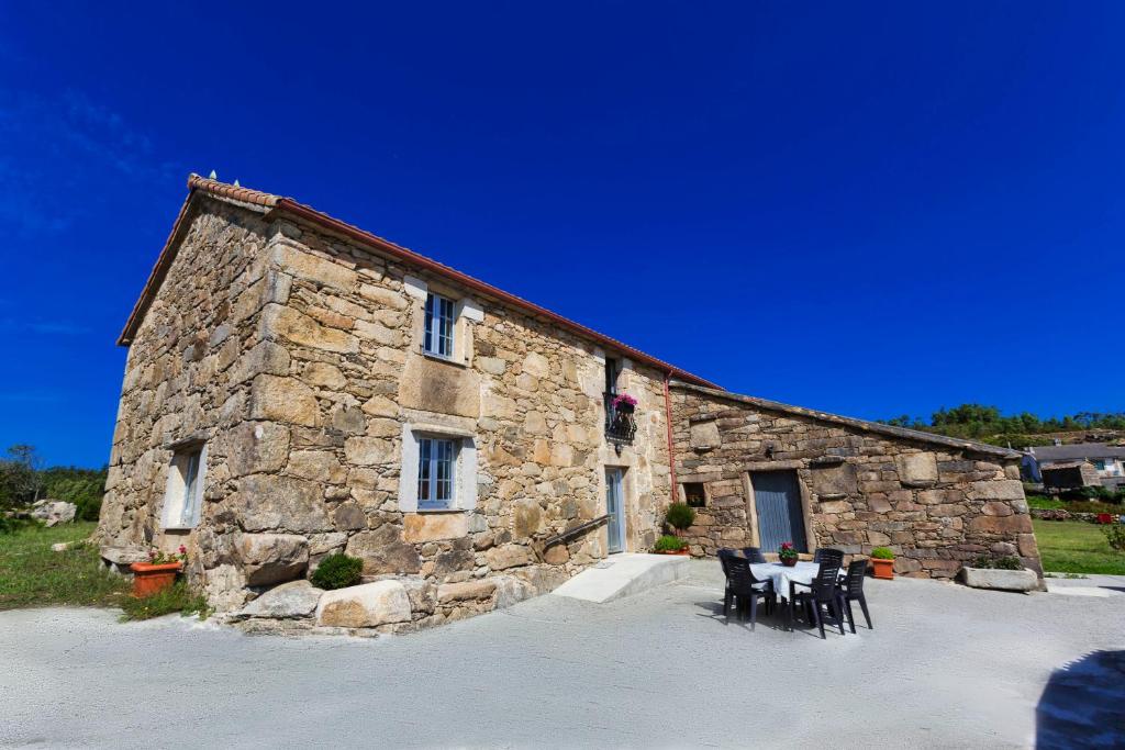 a stone building with chairs and a table in front of it at Casa de Valente - Camariñas in Camariñas