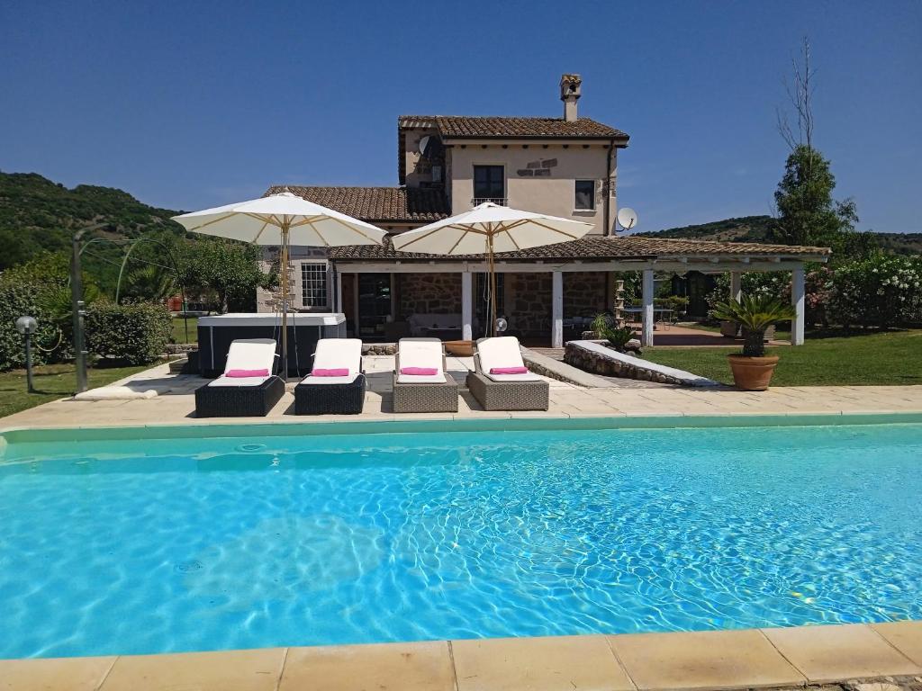 - une piscine avec des chaises et des parasols en face d'une maison dans l'établissement Villa in Campagna con Piscina Privata, à Uri