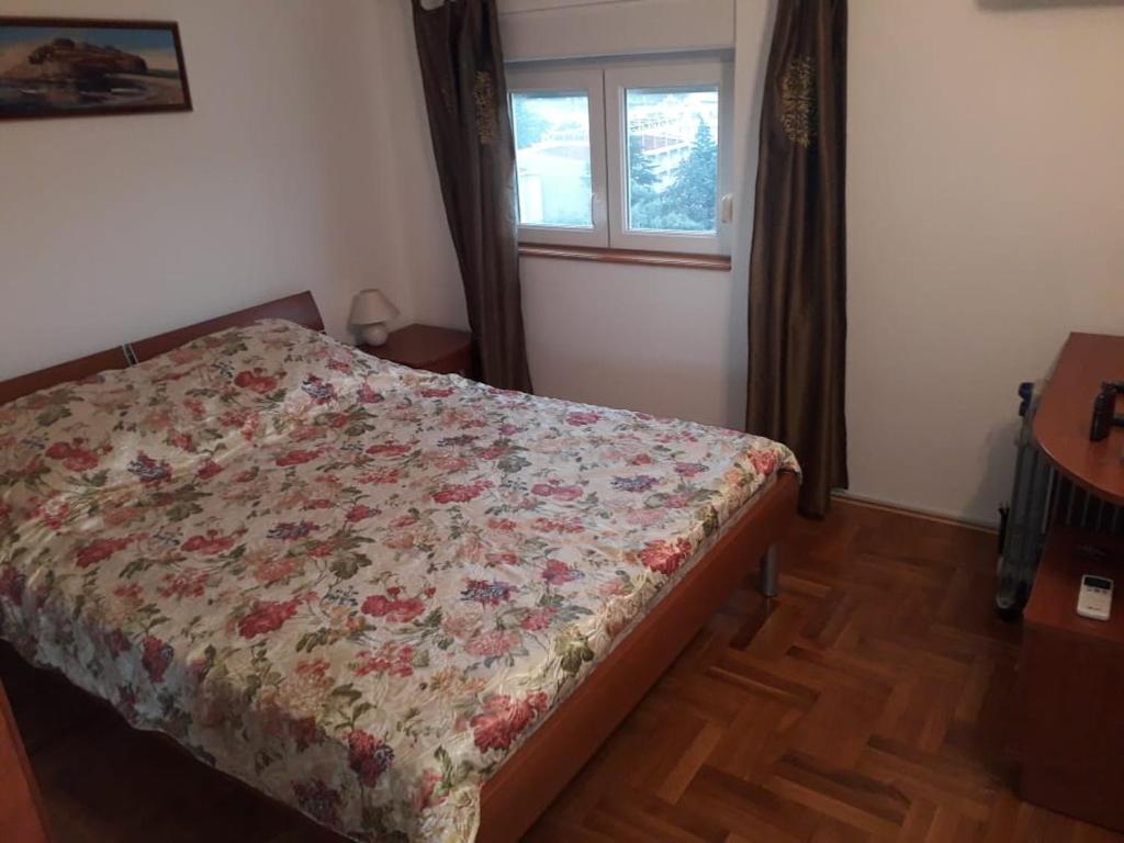 - une chambre avec un lit avec une couette à fleurs et une fenêtre dans l'établissement VITALY, à Petrovac na Moru