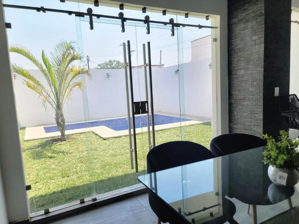 une salle à manger avec une table en verre et une vue sur la cour dans l'établissement Casa Villa Teques, à Tequesquitengo