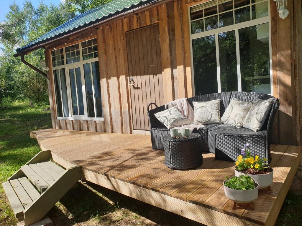 un porche cubierto con un sofá en una terraza de madera en Pūču māja/Owl house namiņš Ogrē en Ogre