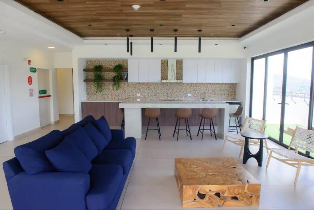 a living room with a blue couch and a kitchen at Skyline Serenity: Luxury Retreat in Tegucigalpa in Tegucigalpa