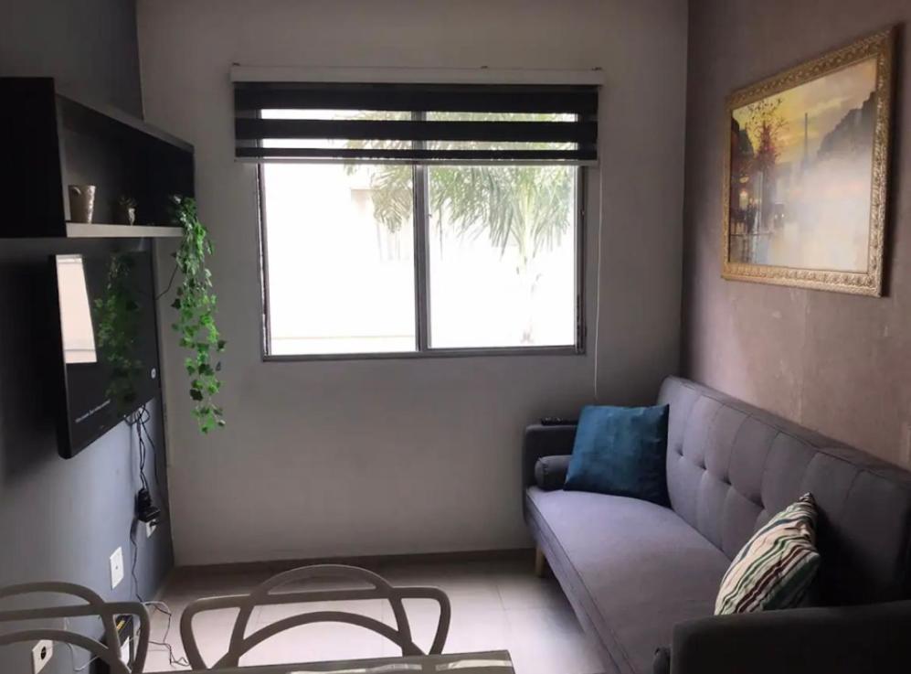 een woonkamer met een bank en een raam bij Apartamento aconchegante perto do Shopping Iguatemi in Votorantim