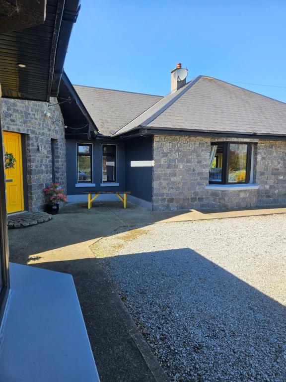 a house with a yellow door and a driveway at Ard Aoibhinn Roscommon in Lecarrow