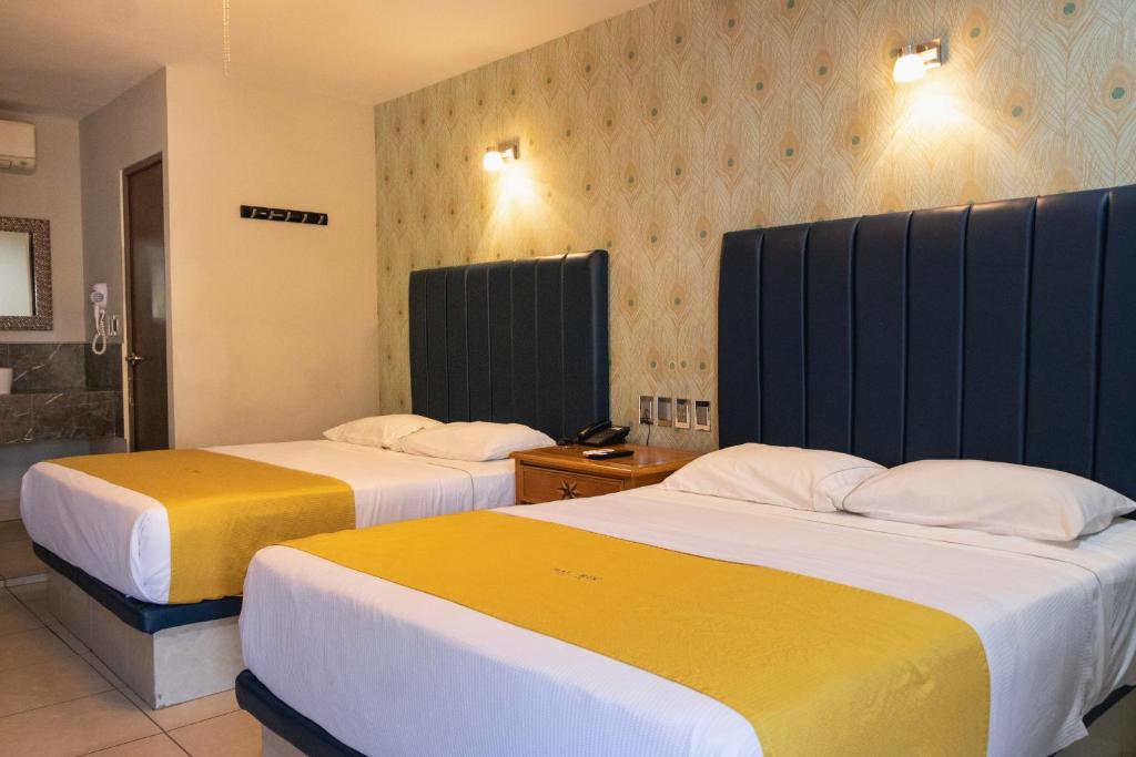 Dos camas en una habitación de hotel con amarillo y blanco en Hotel Maioris El Diez Culiacan, en Culiacán