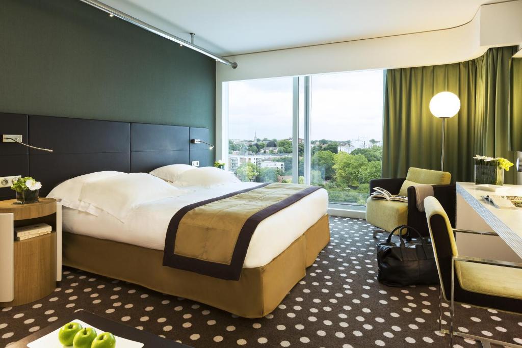 リールにあるホテル バリエール リールの大きなベッドと椅子が備わるホテルルームです。
