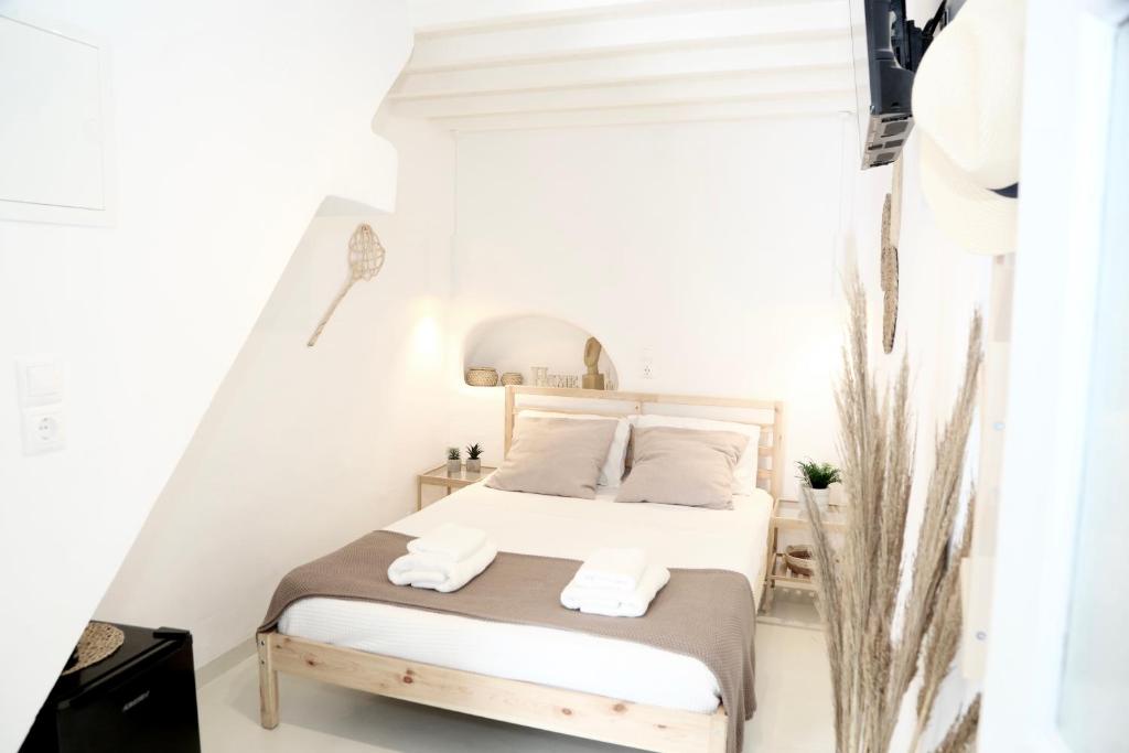 1 dormitorio blanco con 1 cama y 2 toallas en Whitelist Studios in Mykonos Town en Mykonos ciudad