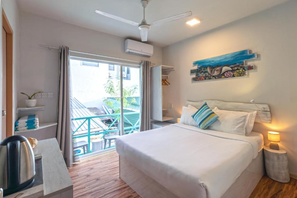 Ocean Pearl Maldives at Gulhi Island في غولهي: غرفة نوم بسرير ونافذة كبيرة