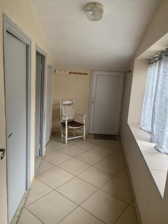 un couloir vide avec une chaise et une fenêtre dans l'établissement la clède aux lamas, à Vébron