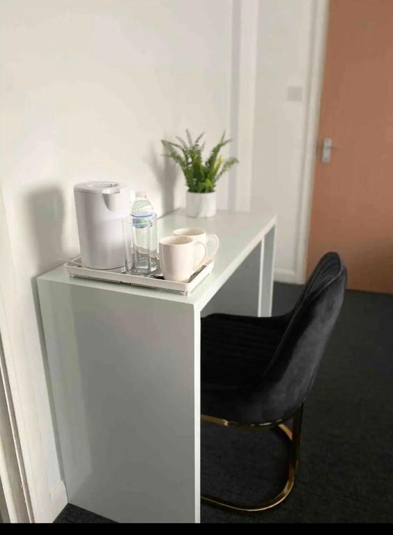 a white desk with a chair and a bottle of water at Luxury king en-suite room in Peterborough
