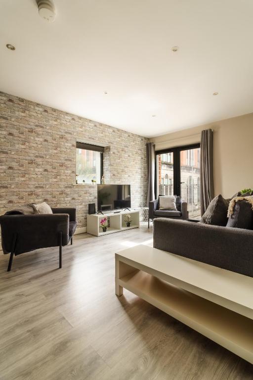 a living room with two couches and a brick wall at Belfast Quarters: Modern City Centre Hub 3 Bed in Belfast