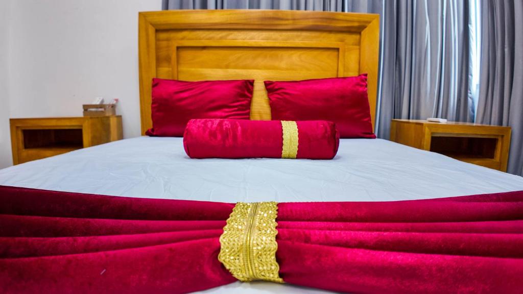 1 cama grande con sábanas rojas y blancas y almohadas rojas en MODERNO APARTAMENTO AMBUELADO TOTALMENTE NUEVO., en Bonao