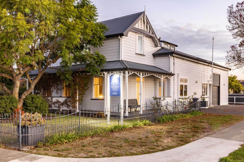 Una casa blanca con un cartel azul. en Havelock Homestead en Havelock North