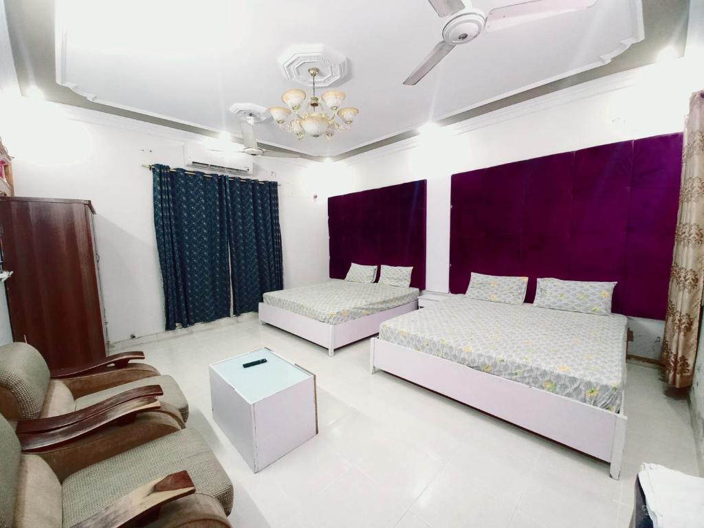 2 Betten in einem Zimmer mit lila Vorhängen in der Unterkunft Guest House Rose Palace in Karatschi