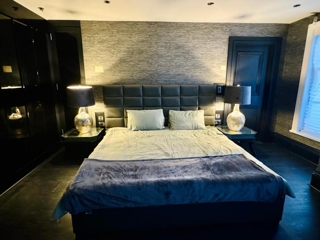 een slaapkamer met een groot bed met 2 lampen bij Chigwell Mansion in Theydon Bois