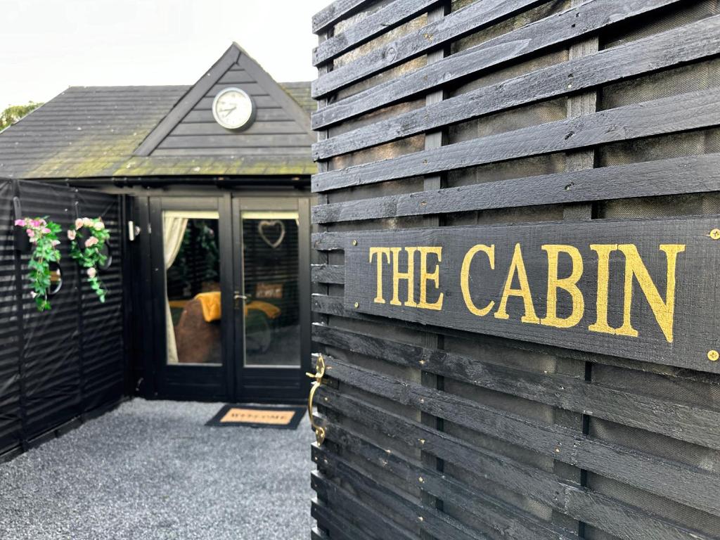 a sign that says the cabin on the side of a building at The Cabin Near Stansted Airport in Little Hallingbury