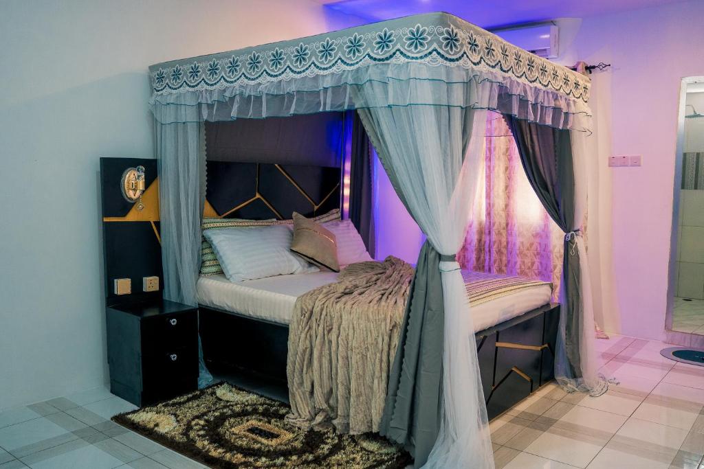 - une chambre avec un lit à baldaquin et un éclairage violet dans l'établissement GE-Homes, à Dar es Salaam