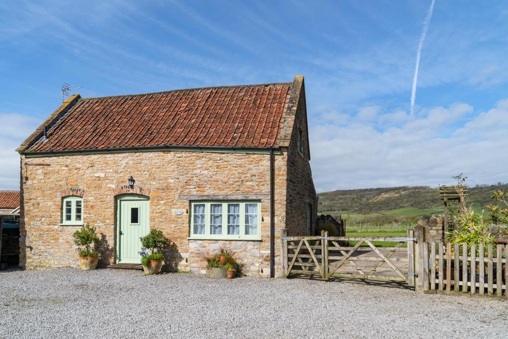 uma casa de tijolos com uma porta verde e uma cerca em Coachmans Cottage in Loxton em Loxton