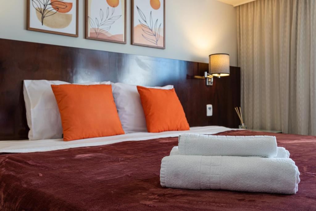 ein Schlafzimmer mit einem großen Bett mit orangefarbenen und weißen Kissen in der Unterkunft Maximus Luxury in Wyn Berrini - WTC II in São Paulo