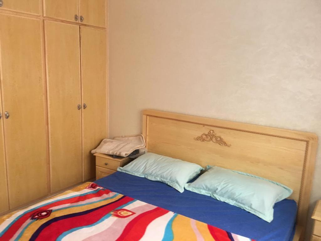 een bed met een houten hoofdeinde in een slaapkamer bij Appartement Plage & Famille in Ras El Ma