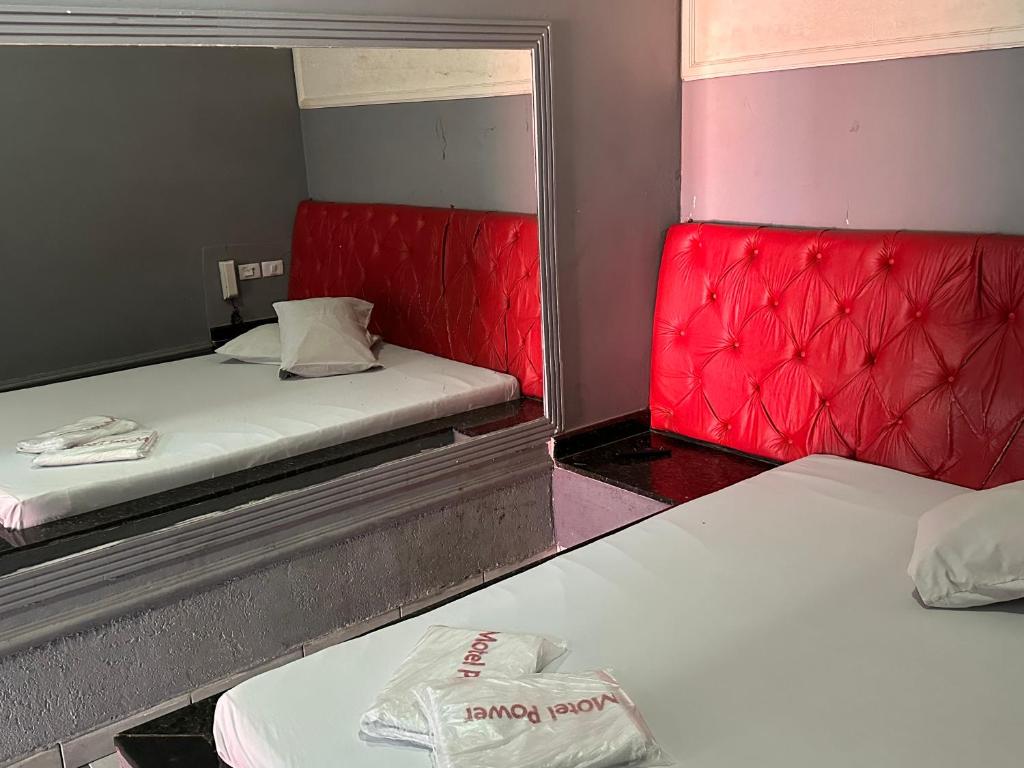 2 posti letto in una piccola stanza con sedili rossi di Motel Power a Belo Horizonte