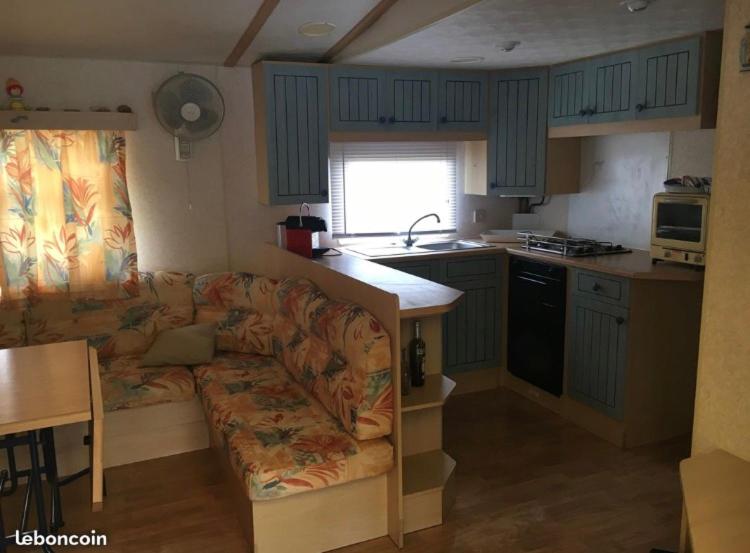 a living room with a couch and a kitchen at Mobilhome Vieux Boucau les bains in Vieux-Boucau-les-Bains