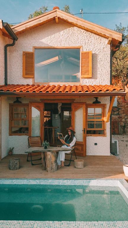 a woman sitting on a chair in front of a house at Loft Country Kaş in Kaş