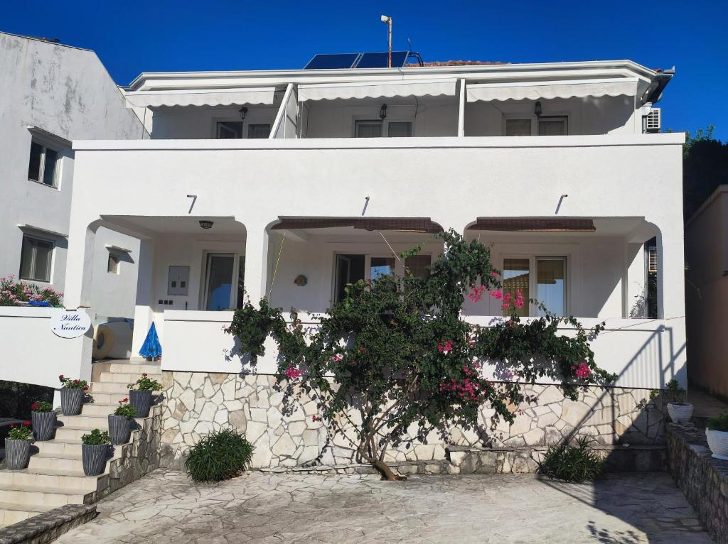 a white house with a tree in front of it at Villa Nautica in Lustica