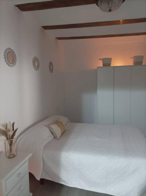 Un dormitorio blanco con una cama y una mesita de noche. en El Salero, en Villargordo del Cabriel