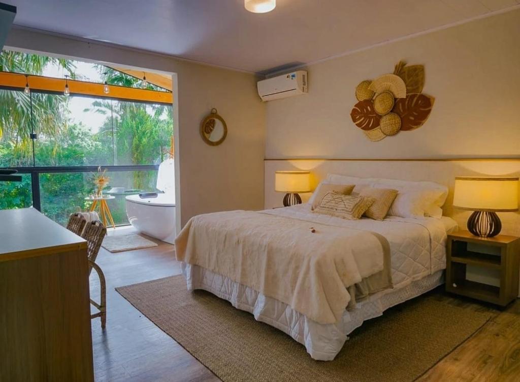 a bedroom with a bed and a bathroom with a tub at Hotel Sonnet by Estância Santa Cruz in Curitiba
