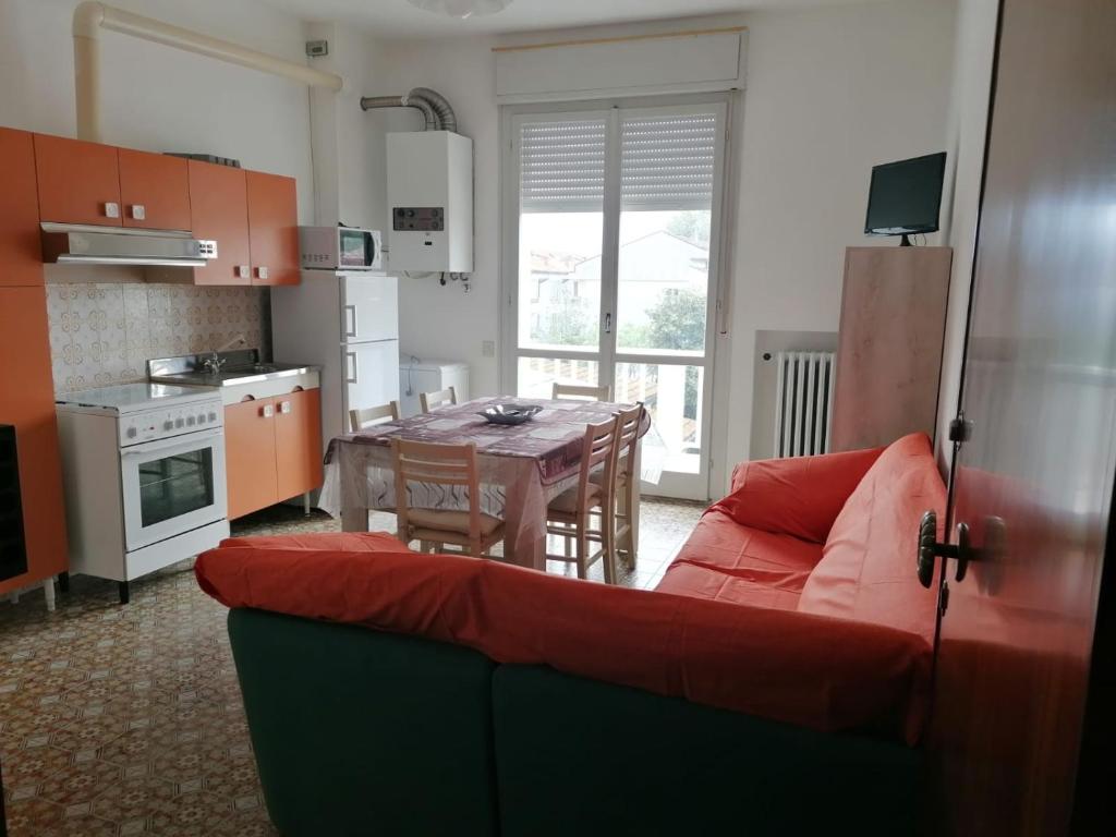 sala de estar con sofá rojo y mesa en Appartamento dei Pavoni, en Punta Marina